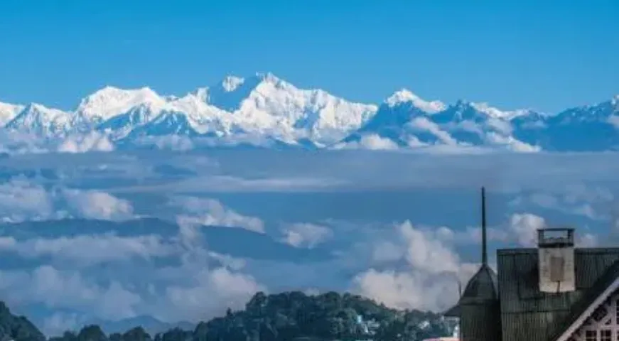 Panoramic view of Mount Kanchenjunga peaks over the colorful Darjeeling town under a clear blue sky.