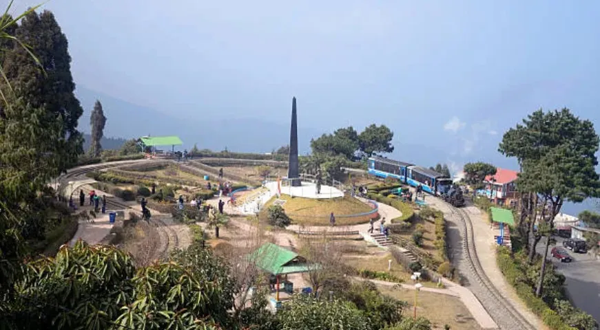 Darjeeling Toy Train crossing the Batasia Loop greenery with mountains.